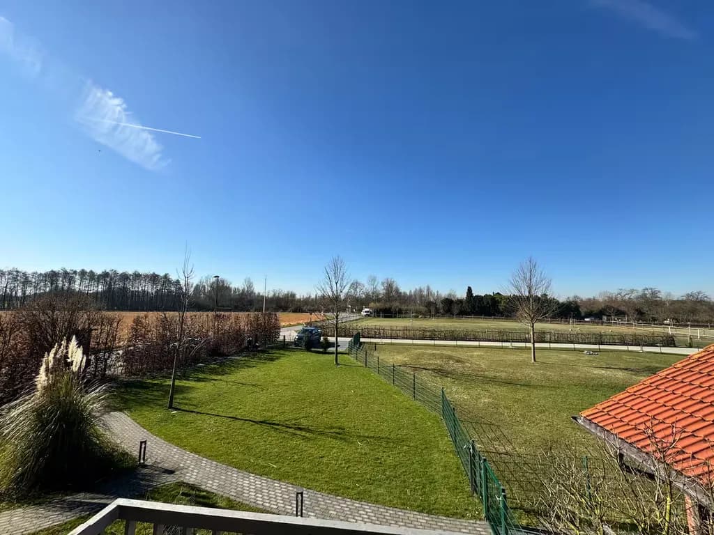 Ausblick vom Balkon der Ferienwohnung auf grüne Weiden und die Alpaka-Koppel
