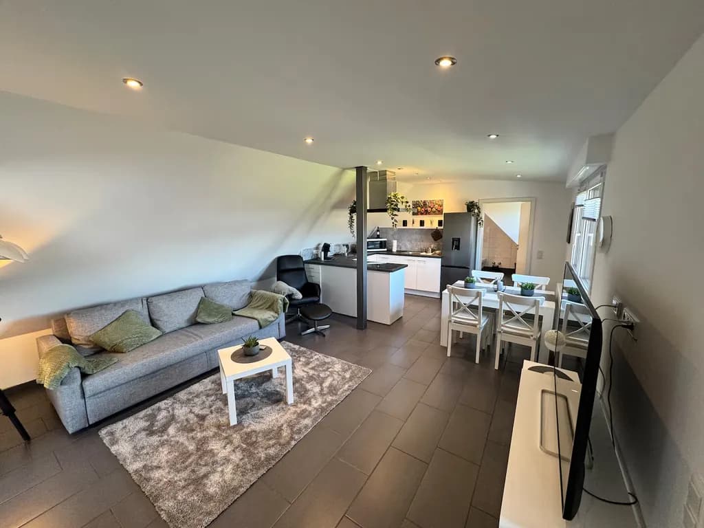 Offener Wohnbereich der Ferienwohnung mit Sofa, Essbereich und Küche